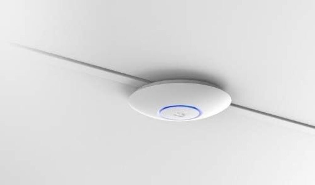 Um equipamento de Access Point instalado no teto de uma sala.