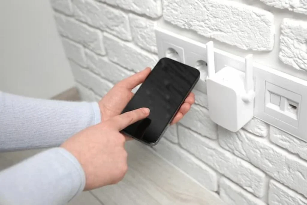 Uma pessoa próxima ao repetidor de sinal Wi-fi analisando sua conexão.